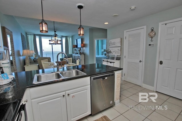 kitchen with dark countertops, stainless steel dishwasher, white cabinets, a sink, and range