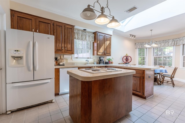 kitchen with light tile patterned floors, a center island, white appliances, and light countertops