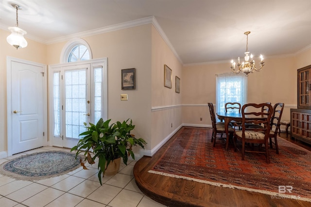 tiled dining area with an inviting chandelier, baseboards, and crown molding