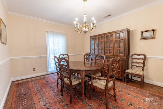 dining room featuring visible vents, crown molding, wood finished floors, baseboards, and a notable chandelier