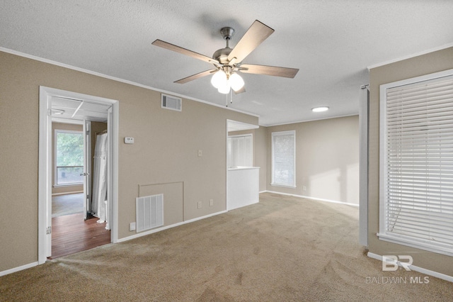 unfurnished room with ceiling fan, light colored carpet, a textured ceiling, and ornamental molding