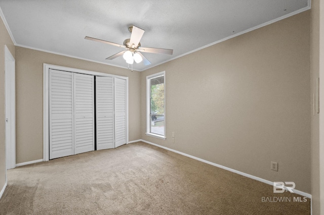 unfurnished bedroom with carpet flooring, ceiling fan, ornamental molding, and a closet