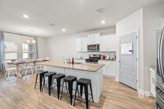 kitchen with light wood-style flooring, stainless steel appliances, a breakfast bar, a sink, and tasteful backsplash