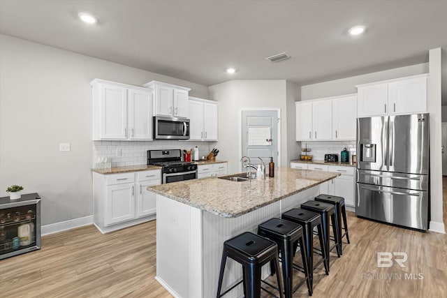 kitchen featuring appliances with stainless steel finishes, visible vents, a sink, and light wood-style flooring