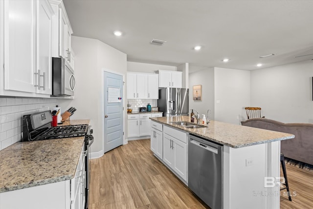 kitchen with light wood-style flooring, a breakfast bar, a sink, visible vents, and appliances with stainless steel finishes