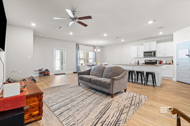 living room with light wood-type flooring, visible vents, and recessed lighting