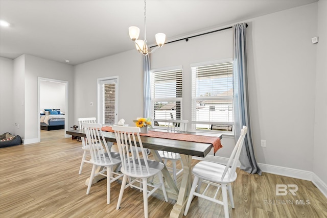 dining area with light wood-type flooring, a notable chandelier, and baseboards