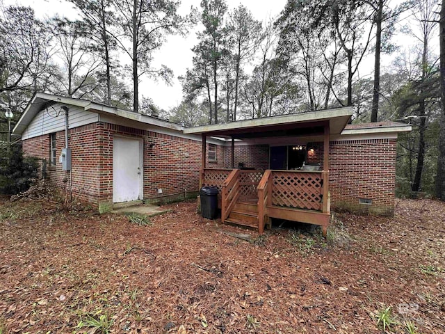 rear view of house featuring a deck, brick siding, and crawl space