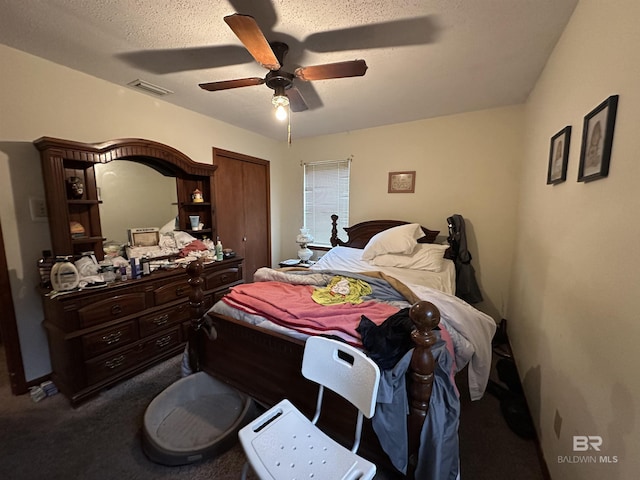 bedroom with visible vents, dark colored carpet, a closet, and ceiling fan