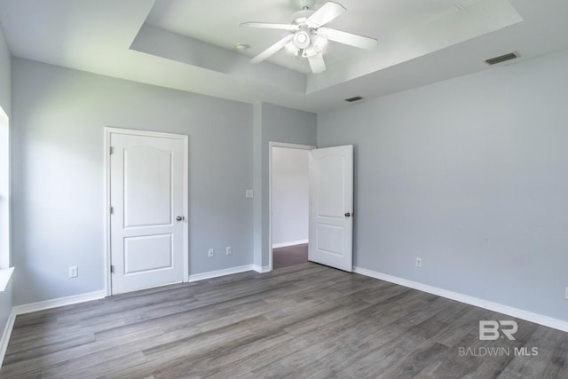 4005 Serene Ct, Foley, AL 36535 - unfurnished bedroom with visible vents, baseboards, a tray ceiling, and wood finished floors