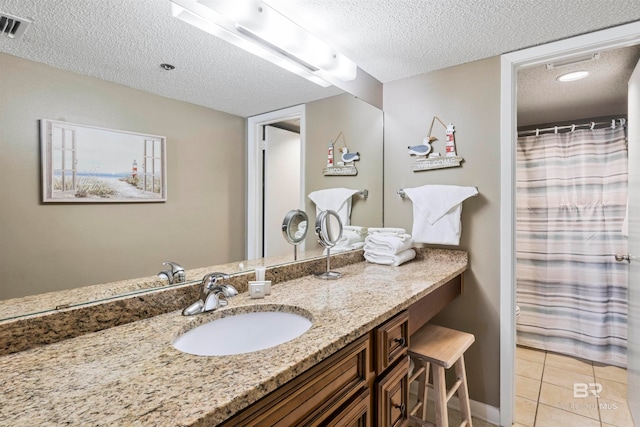 bathroom with a textured ceiling, vanity, and tile patterned floors