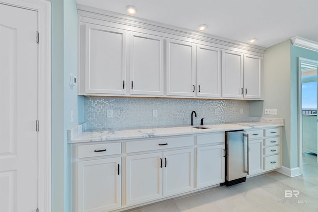 kitchen with light stone countertops, white cabinetry, backsplash, and refrigerator