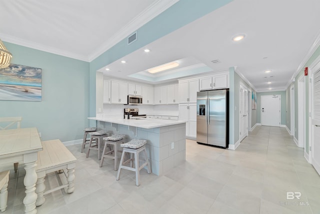 kitchen featuring a peninsula, visible vents, stainless steel appliances, and ornamental molding