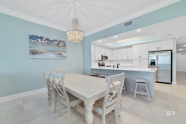 dining room featuring a tray ceiling, crown molding, visible vents, a chandelier, and baseboards