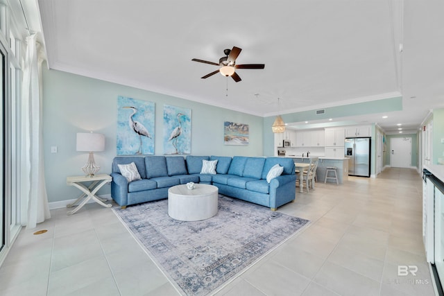 living room with ornamental molding, ceiling fan, baseboards, and light tile patterned floors