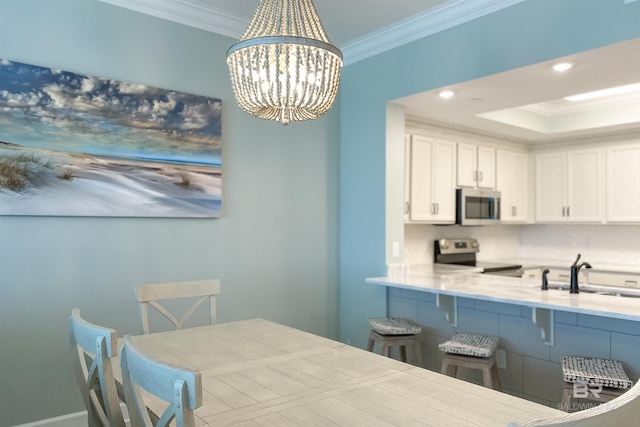 kitchen featuring appliances with stainless steel finishes, a notable chandelier, crown molding, and a sink