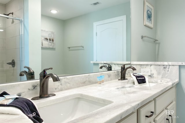 bathroom featuring double vanity, a sink, visible vents, and a shower stall