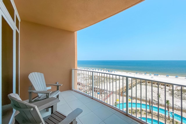 balcony featuring a view of the beach and a water view