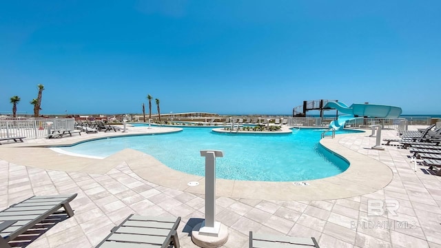 pool with fence, a water slide, and a patio