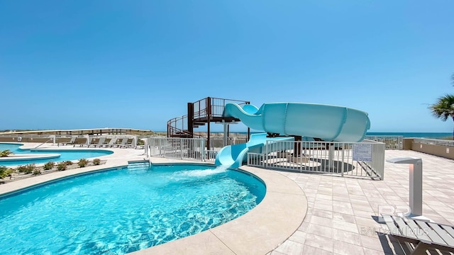 pool with fence, a water slide, and a patio