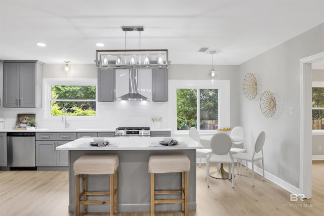 300 Indian Creek Dr, Mobile, AL 36607 - kitchen featuring gray cabinets, appliances with stainless steel finishes, wall chimney range hood, a sink, and light wood-style flooring