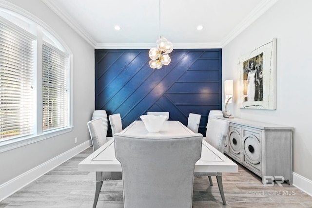 dining space featuring crown molding, light wood-type flooring, and an inviting chandelier