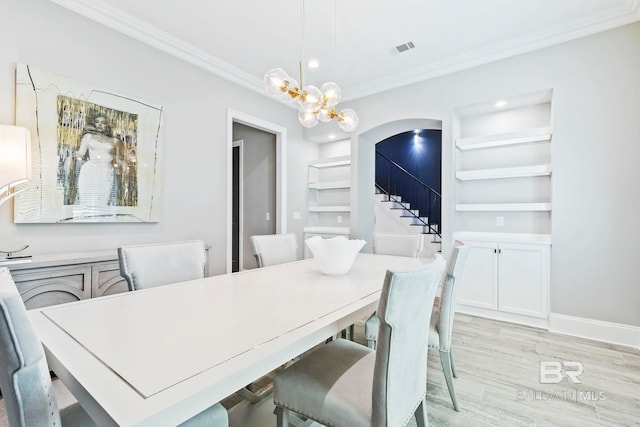 dining area featuring ornamental molding, built in shelves, a notable chandelier, and light hardwood / wood-style flooring