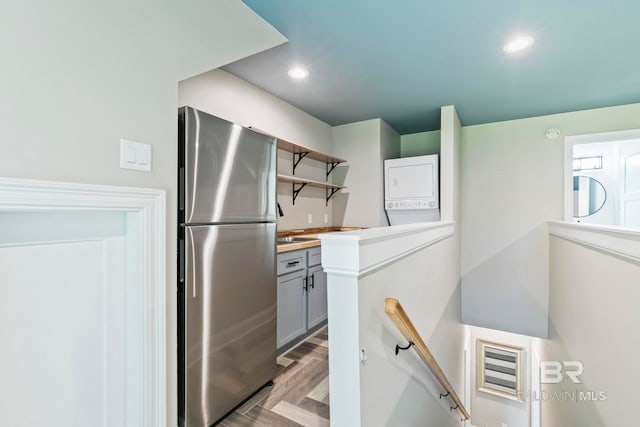 kitchen featuring stacked washer and clothes dryer, stainless steel fridge, gray cabinets, and light hardwood / wood-style floors