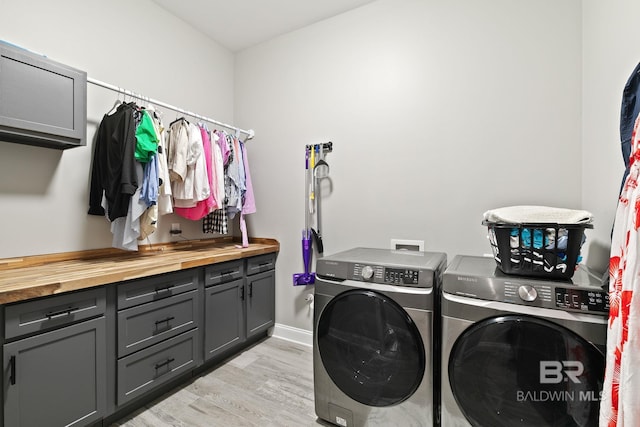 washroom with cabinets, washer and dryer, and light hardwood / wood-style flooring