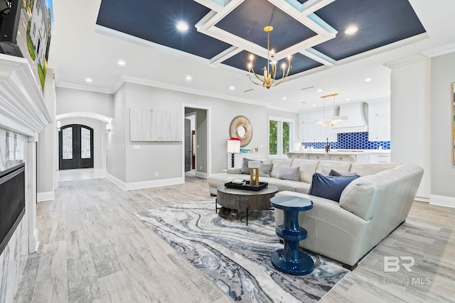 living room featuring french doors, crown molding, a chandelier, and light hardwood / wood-style floors