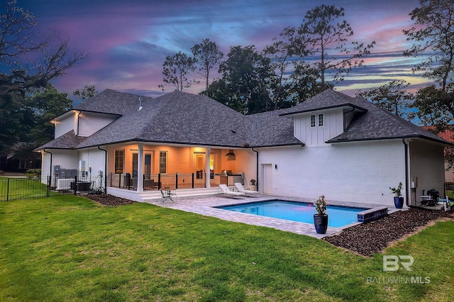 back house at dusk with a fenced in pool, a yard, and a patio area