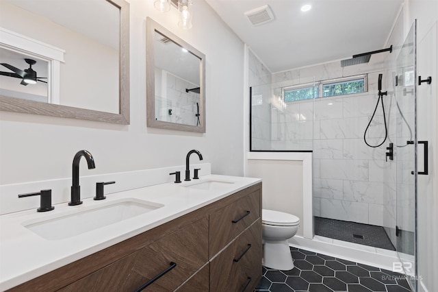 bathroom featuring a tile shower, tile patterned flooring, vanity, ceiling fan, and toilet