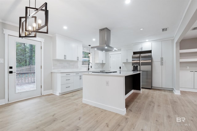 kitchen featuring hanging light fixtures, stainless steel refrigerator with ice dispenser, island range hood, white cabinets, and a kitchen island