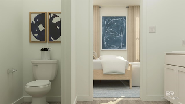 bathroom featuring toilet, wood finished floors, ensuite bathroom, baseboards, and vanity