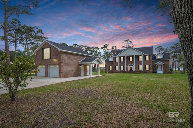 neoclassical home featuring a garage and a yard