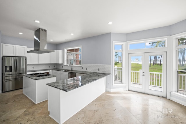 kitchen featuring island range hood, backsplash, appliances with stainless steel finishes, and a wealth of natural light