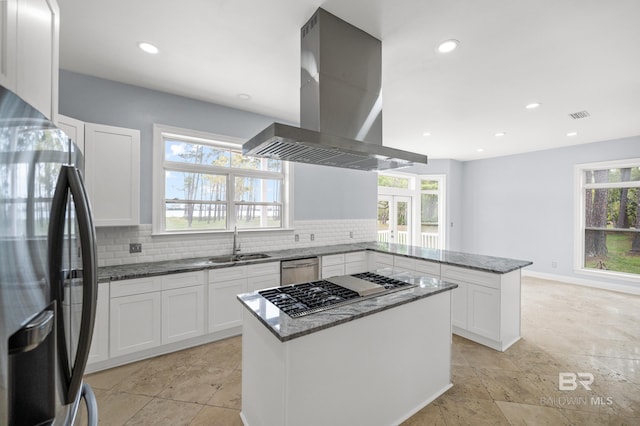 kitchen with dark stone counters, stainless steel appliances, island exhaust hood, and decorative backsplash