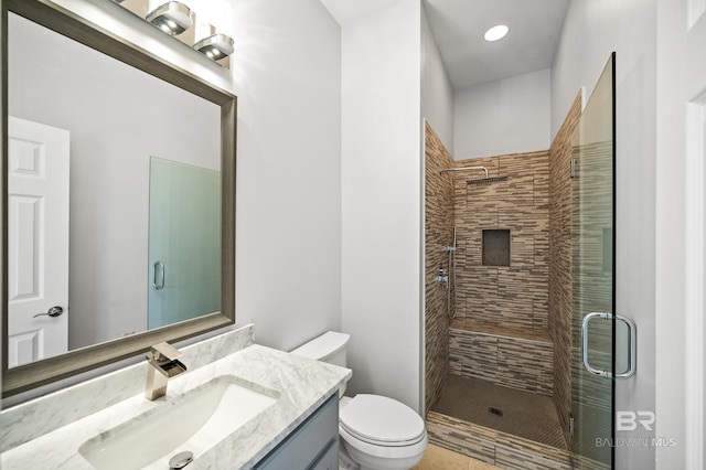 bathroom featuring a shower with door, toilet, and vanity