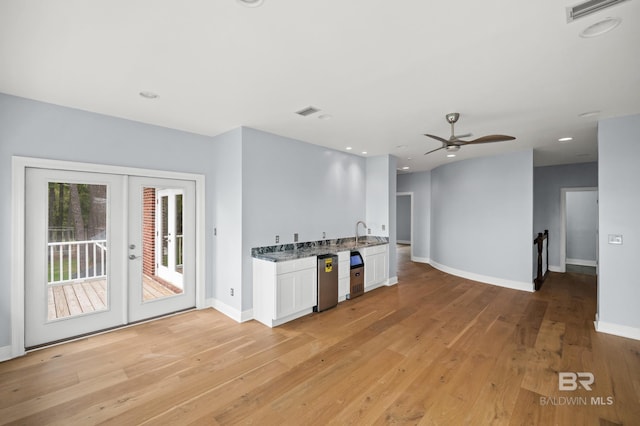 kitchen with light hardwood / wood-style floors, french doors, sink, white cabinets, and ceiling fan