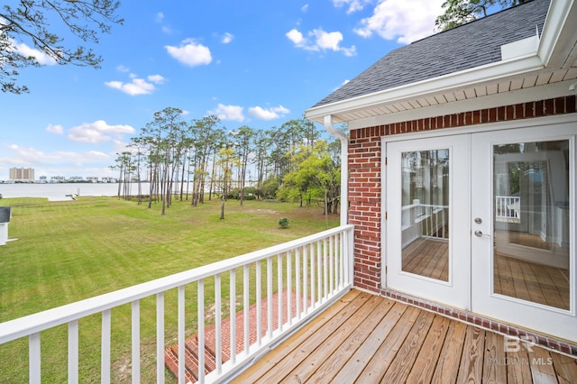 wooden deck featuring a water view, a yard, and french doors