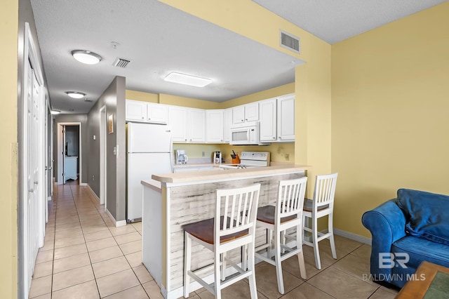 kitchen featuring white cabinets, kitchen peninsula, and white appliances