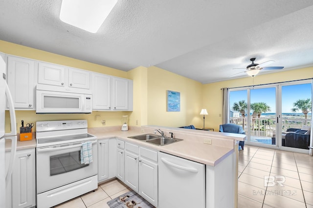 kitchen with white appliances, light tile patterned flooring, sink, kitchen peninsula, and white cabinets