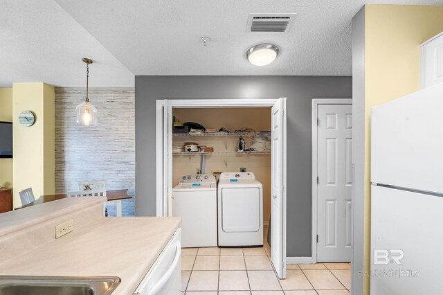 laundry room featuring washer and dryer, a textured ceiling, and light tile patterned flooring