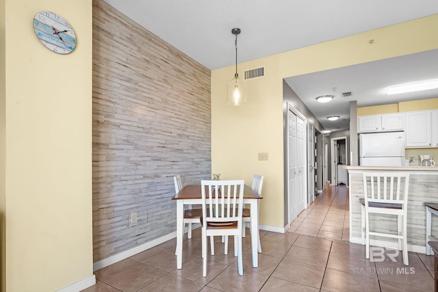 unfurnished dining area with dark tile patterned flooring and wooden walls