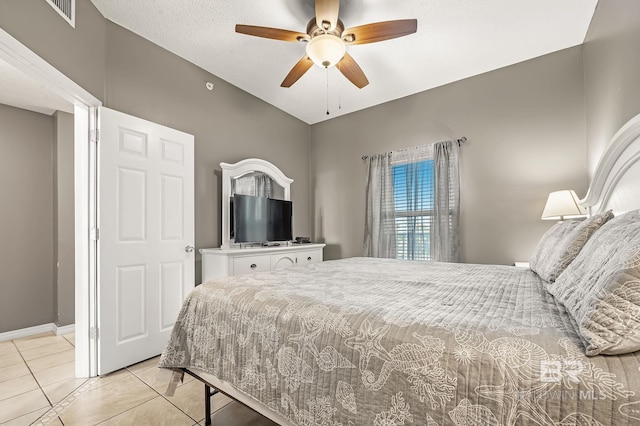 tiled bedroom with ceiling fan and a textured ceiling