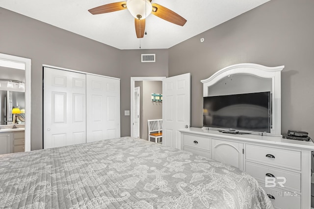 bedroom featuring a closet, ensuite bathroom, sink, and ceiling fan