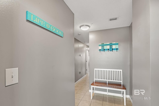 hallway with a textured ceiling and light tile patterned floors