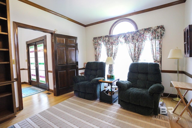 sitting room with french doors, light wood-type flooring, and crown molding