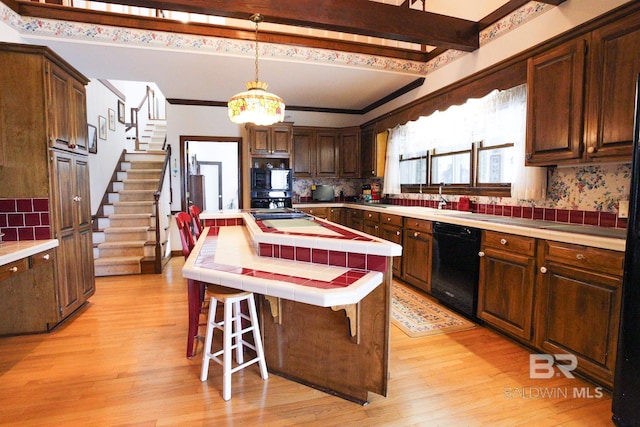 kitchen featuring light wood-type flooring, black appliances, backsplash, and tile countertops