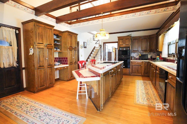 kitchen with hanging light fixtures, a center island, light hardwood / wood-style floors, double oven, and backsplash